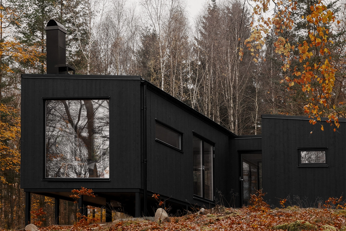 Modulhus e-länk, svart hus på tomt i naturen